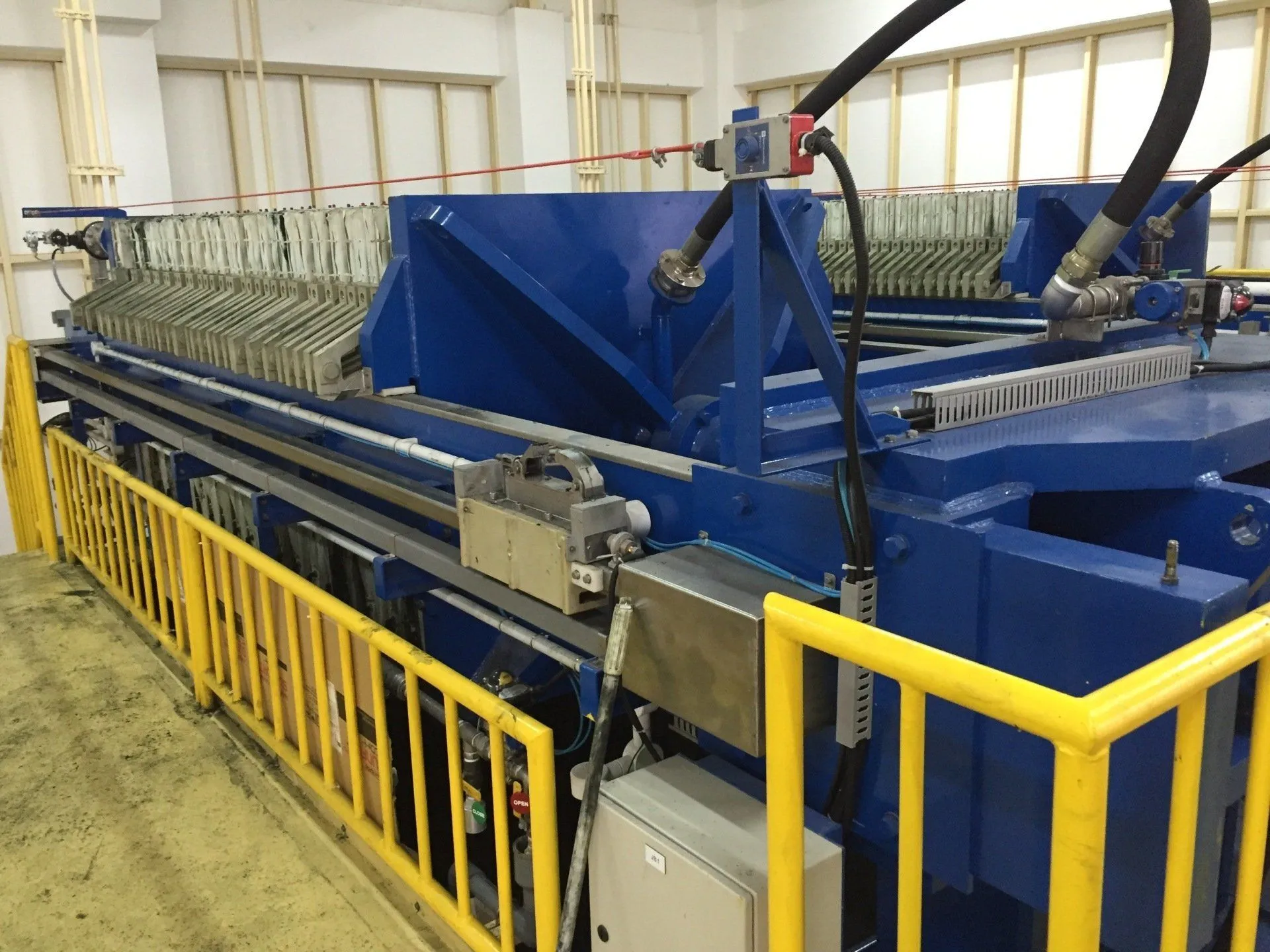 Large blue filter press with yellow safety rails